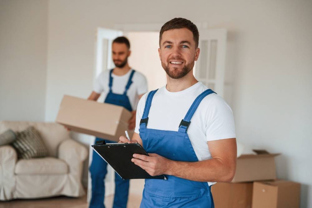 Document in hands. Two moving service employees in a room.
