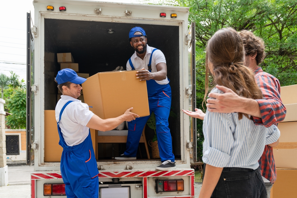 Man movers worker in blue uniform unloading cardboard boxes from truck.Professional delivery and moving service